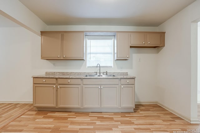 318 Elks, San Antonio, TX 78211 - kitchen featuring a sink, light wood-type flooring, baseboards, and light stone counters