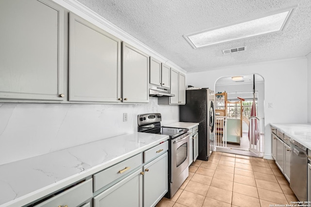 4838 Corian Spgs, San Antonio, TX 78247 - kitchen featuring appliances with stainless steel finishes, under cabinet range hood, a textured ceiling, light stone countertops, and light tile patterned floors
