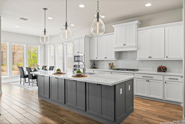 kitchen with a sink, recessed lighting, gray cabinetry, light countertops, and decorative backsplash