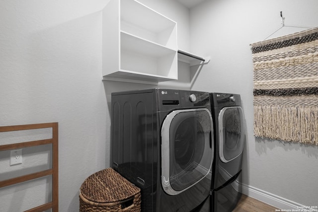clothes washing area featuring washing machine and dryer, wood finished floors, and baseboards