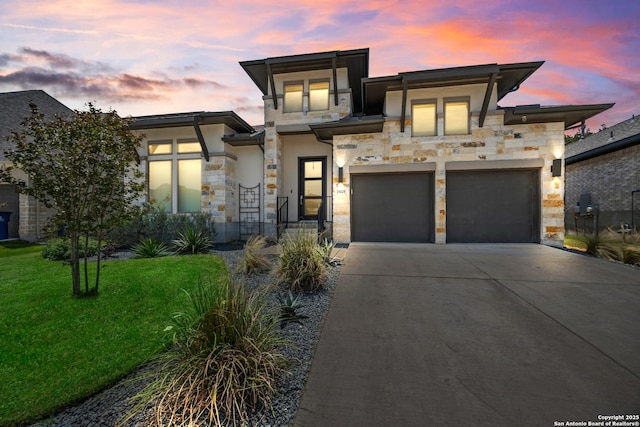 view of front of home with stone siding, driveway, a front yard, an attached garage, and stucco siding