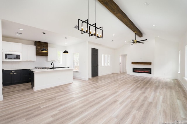 580 Compass Rose, Canyon Lake, TX 78133 - unfurnished living room featuring beam ceiling, recessed lighting, a glass covered fireplace, high vaulted ceiling, and a sink