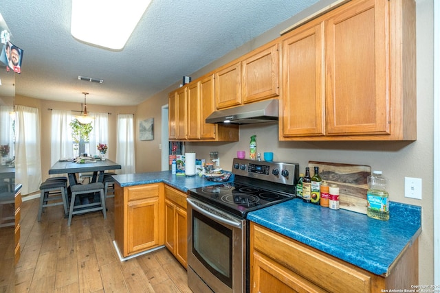 8013 County Road 128, Floresville, TX 78114 - kitchen with under cabinet range hood, electric range, light wood finished floors, dark countertops, and a textured ceiling