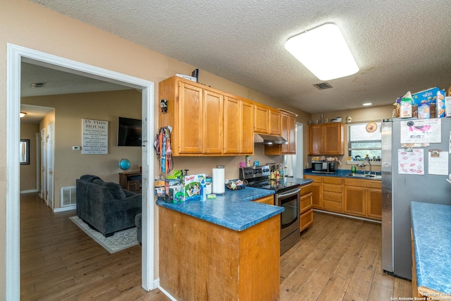 8013 County Road 128, Floresville, TX 78114 - kitchen with appliances with stainless steel finishes, under cabinet range hood, a sink, light wood finished floors, and a textured ceiling