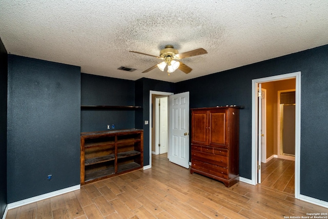 8013 County Road 128, Floresville, TX 78114 - unfurnished bedroom with light wood-style floors, baseboards, a textured ceiling, and ceiling fan