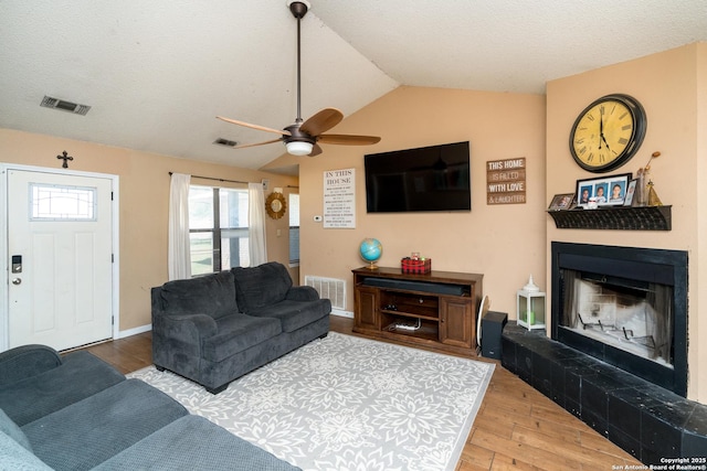 8013 County Road 128, Floresville, TX 78114 - living room with vaulted ceiling, a fireplace with raised hearth, wood finished floors, and a ceiling fan