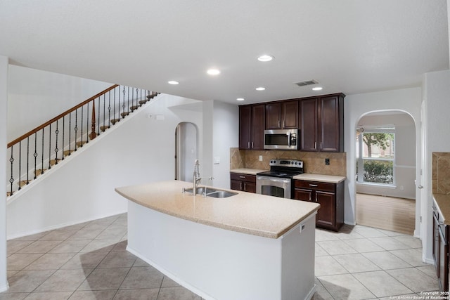 7326 Concerto Dr, San Antonio, TX 78266 - kitchen with appliances with stainless steel finishes, arched walkways, a sink, light tile patterned floors, and decorative backsplash