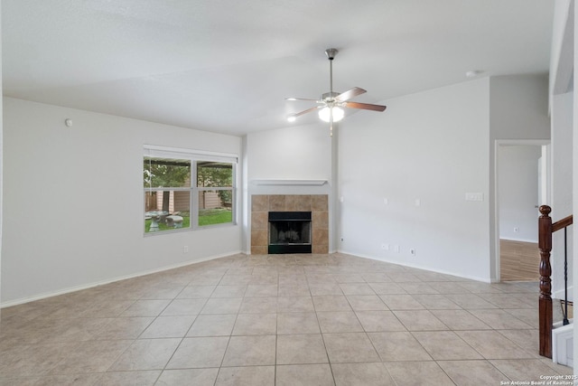 7326 Concerto Dr, San Antonio, TX 78266 - unfurnished living room with a ceiling fan, a tiled fireplace, vaulted ceiling, light tile patterned floors, and baseboards