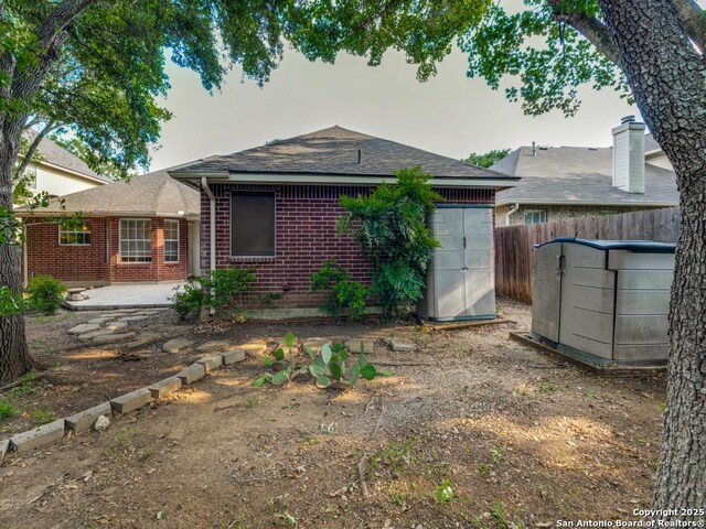 9411 Camino Venado, Helotes, TX 78023 - back of house with brick siding, fence, a patio, and roof with shingles