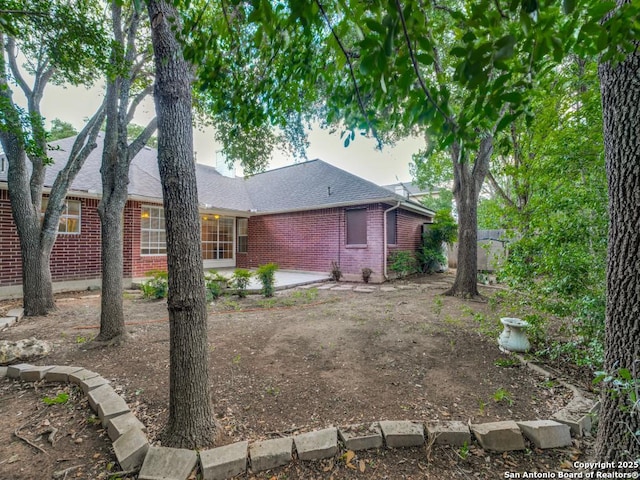 9411 Camino Venado, Helotes, TX 78023 - view of side of property with brick siding, a shingled roof, and a patio