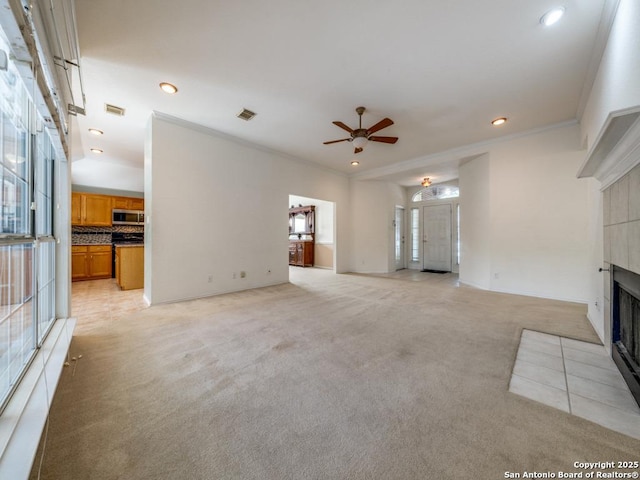 9411 Camino Venado, Helotes, TX 78023 - unfurnished living room featuring a tiled fireplace, light carpet, ceiling fan, recessed lighting, and crown molding