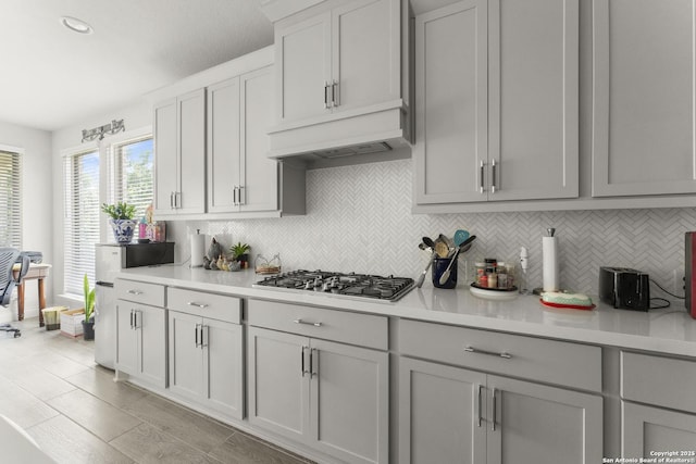 63 Ricadonna, San Antonio, TX 78253 - kitchen featuring stainless steel gas cooktop, backsplash, light countertops, under cabinet range hood, and gray cabinetry