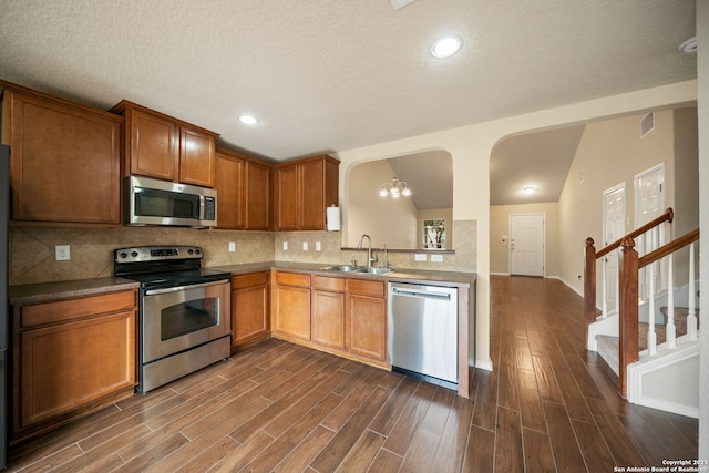 10438 Sun Ml, San Antonio, TX 78254 - kitchen with appliances with stainless steel finishes, a sink, decorative backsplash, dark wood finished floors, and brown cabinetry