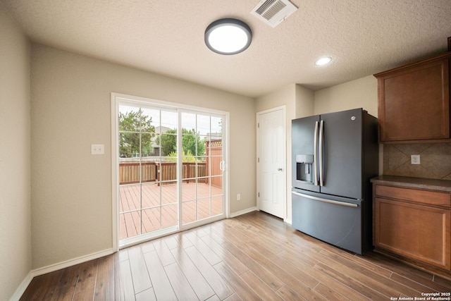 10438 Sun Ml, San Antonio, TX 78254 - kitchen featuring stainless steel refrigerator with ice dispenser, baseboards, wood finished floors, dark countertops, and a textured ceiling