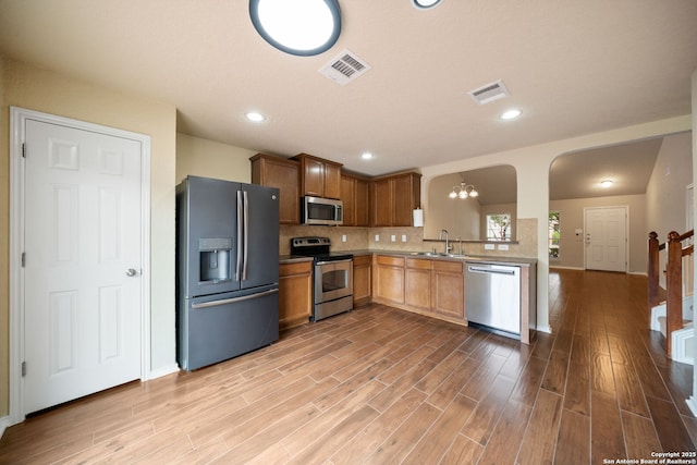 10438 Sun Ml, San Antonio, TX 78254 - kitchen with appliances with stainless steel finishes, wood finished floors, baseboards, a sink, and tasteful backsplash