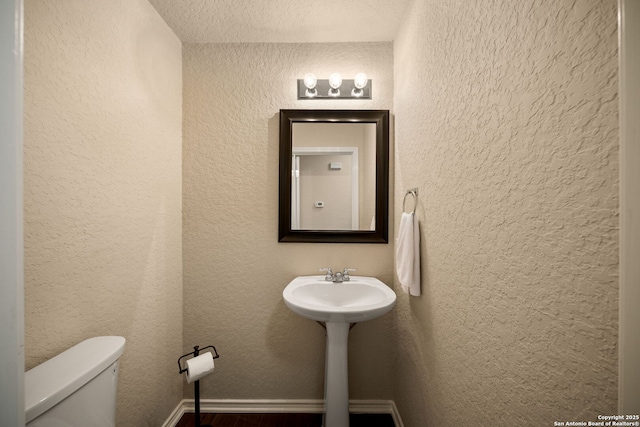 10438 Sun Ml, San Antonio, TX 78254 - half bathroom with wood finished floors, toilet, and a textured wall