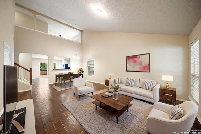 10438 Sun Ml, San Antonio, TX 78254 - living room with dark wood-style flooring, a textured ceiling, high vaulted ceiling, baseboards, and stairway