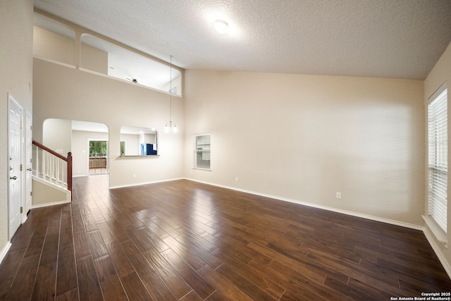 10438 Sun Ml, San Antonio, TX 78254 - unfurnished living room featuring stairs, dark wood-type flooring, high vaulted ceiling, a textured ceiling, and baseboards