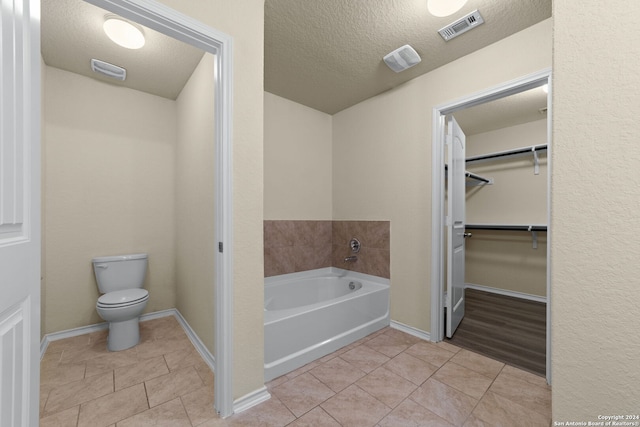 1407 Frio Eagle, San Antonio, TX 78245 - bathroom with toilet, tile patterned flooring, a textured ceiling, a garden tub, and a walk in closet
