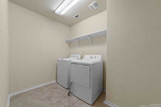 1407 Frio Eagle, San Antonio, TX 78245 - laundry room featuring washing machine and dryer, baseboards, light tile patterned floors, and a textured ceiling