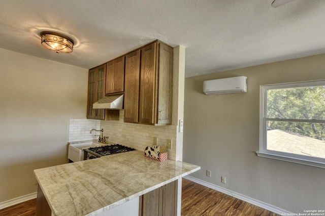 255 Gilbert Ln, San Antonio, TX 78213 - kitchen with a wall unit AC, under cabinet range hood, backsplash, light countertops, and dark wood-type flooring