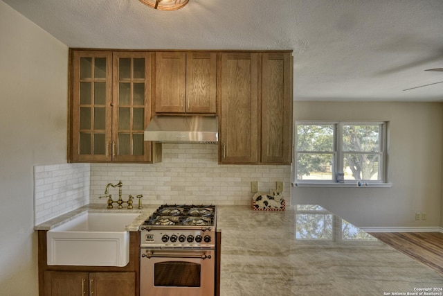 255 Gilbert Ln, San Antonio, TX 78213 - kitchen with exhaust hood, high end range, backsplash, glass insert cabinets, and brown cabinetry