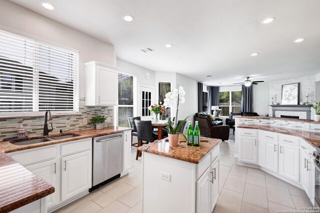 20607 Wild Spgs, San Antonio, TX 78258 - kitchen featuring a sink, appliances with stainless steel finishes, decorative backsplash, a ceiling fan, and a fireplace
