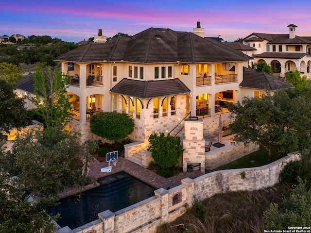 52 Oakland Hls, Boerne, TX 78006 - back of house at dusk featuring a balcony, stucco siding, a patio, and a chimney