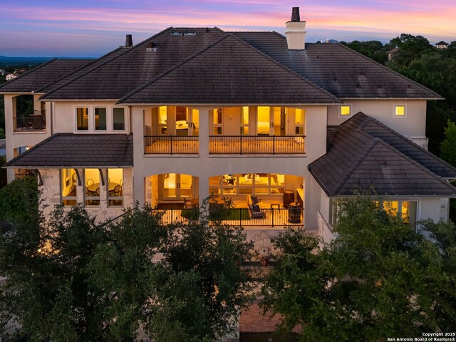 52 Oakland Hls, Boerne, TX 78006 - rear view of property featuring a balcony, a tiled roof, stucco siding, and a chimney
