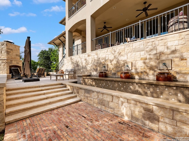 52 Oakland Hls, Boerne, TX 78006 - view of patio featuring an outdoor stone fireplace, a ceiling fan, and a balcony
