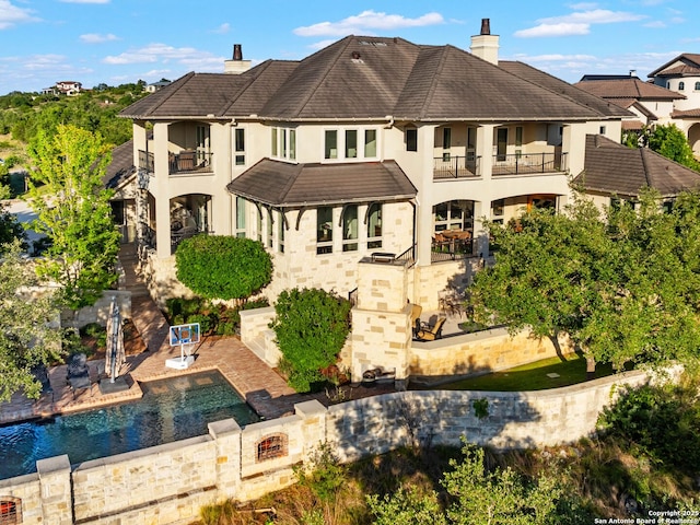 52 Oakland Hls, Boerne, TX 78006 - rear view of house with a balcony, stucco siding, a chimney, an outdoor pool, and a patio area