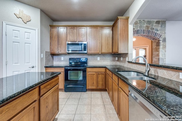 21835 Seminole Oaks, San Antonio, TX 78261 - kitchen featuring appliances with stainless steel finishes, a sink, arched walkways, backsplash, and dark stone counters