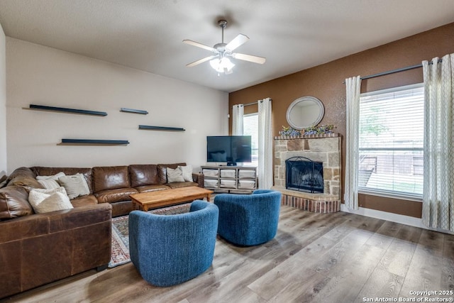 21835 Seminole Oaks, San Antonio, TX 78261 - living room featuring ceiling fan, wood finished floors, a stone fireplace, and baseboards