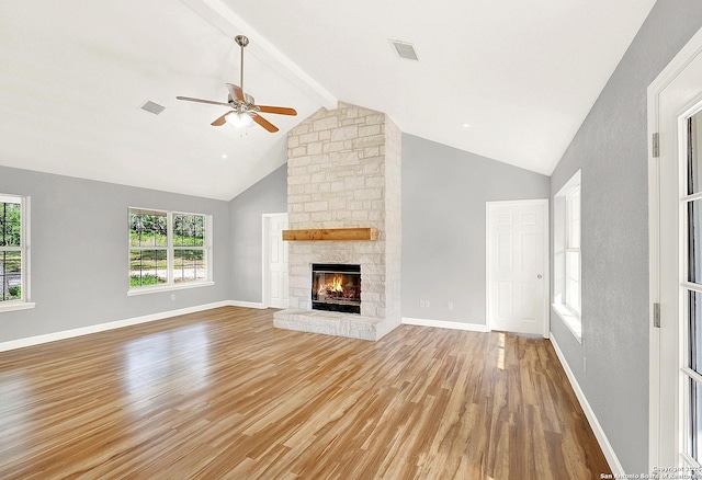 661 Abels Way, Canyon Lake, TX 78133 - unfurnished living room featuring light wood-style floors, a ceiling fan, healthy amount of natural light, beam ceiling, and a stone fireplace