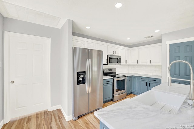 661 Abels Way, Canyon Lake, TX 78133 - kitchen featuring appliances with stainless steel finishes, white cabinets, baseboards, light wood-style flooring, and decorative backsplash