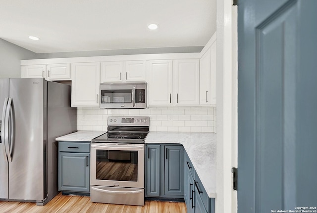 661 Abels Way, Canyon Lake, TX 78133 - kitchen with appliances with stainless steel finishes, gray cabinets, light wood finished floors, white cabinetry, and decorative backsplash