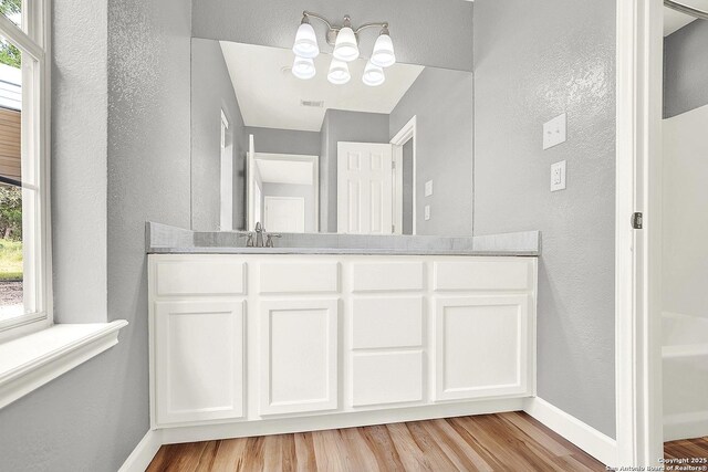 661 Abels Way, Canyon Lake, TX 78133 - bathroom with a textured wall, wood finished floors, a chandelier, baseboards, and vanity