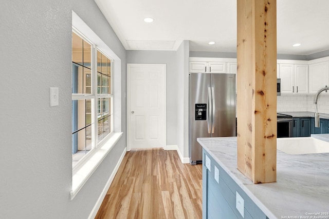 661 Abels Way, Canyon Lake, TX 78133 - kitchen with appliances with stainless steel finishes, white cabinetry, light wood-style floors, baseboards, and decorative backsplash