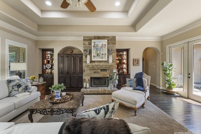 135 Penns Way, Shavano Park, TX 78231 - living room with arched walkways, dark wood-style flooring, a tray ceiling, ceiling fan, and a fireplace