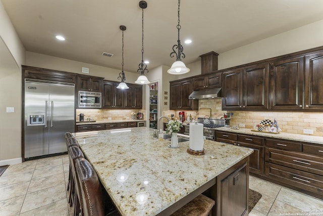 135 Penns Way, Shavano Park, TX 78231 - kitchen with built in appliances, under cabinet range hood, light tile patterned floors, dark brown cabinetry, and tasteful backsplash