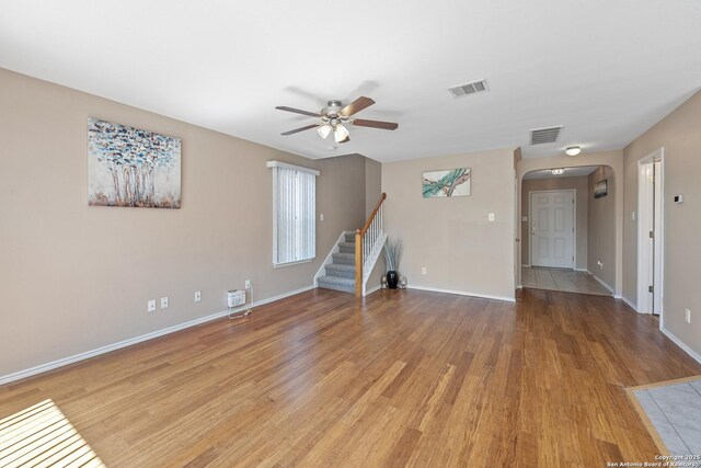 1427 Alaskan Wolf, San Antonio, TX 78245 - unfurnished living room featuring arched walkways, ceiling fan, light wood-type flooring, baseboards, and stairway
