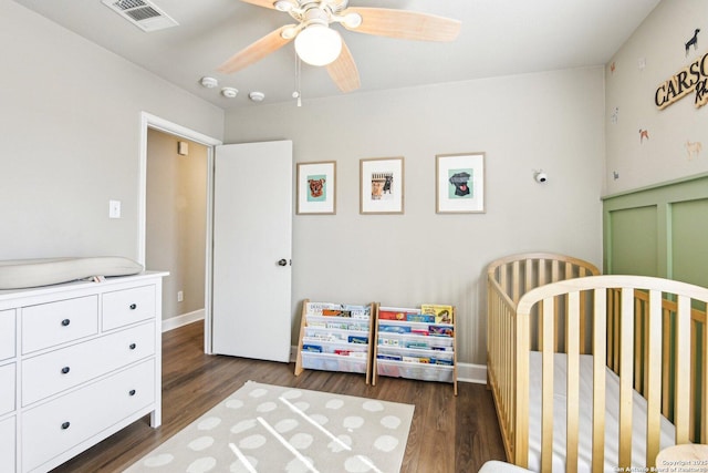 6438 Candleview Ct, San Antonio, TX 78244 - bedroom featuring dark wood-style floors, a crib, baseboards, and a ceiling fan