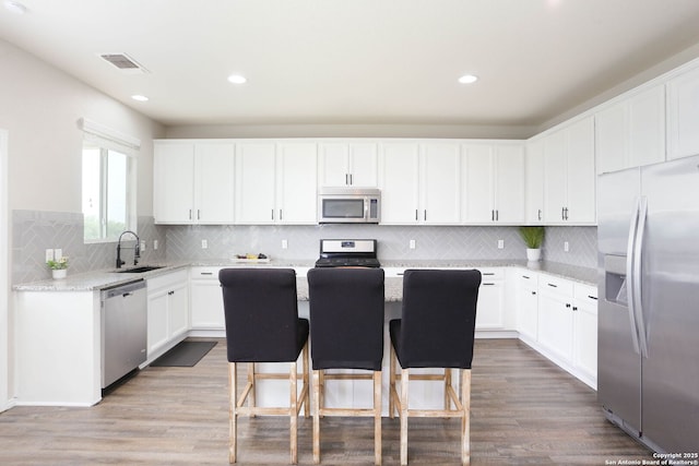 12890 Limestone Way, San Antonio, TX 78253 - kitchen featuring stainless steel appliances, a sink, white cabinetry, wood finished floors, and recessed lighting