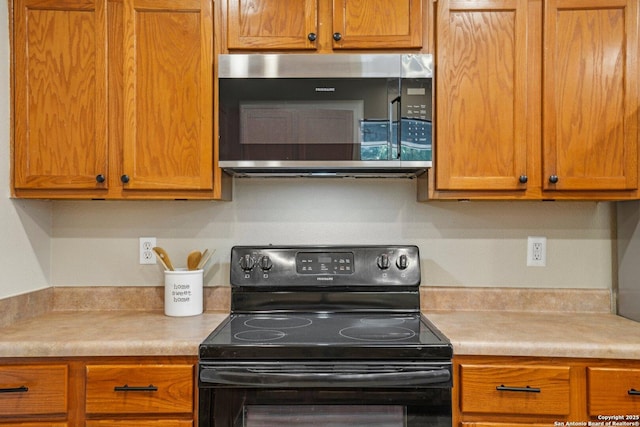 7230 Sunrise Lk, San Antonio, TX 78244 - kitchen featuring black electric range oven, stainless steel microwave, light countertops, and brown cabinets