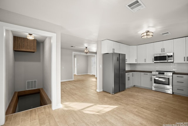 402 Twin Elm, Canyon Lake, TX 78133 - kitchen with appliances with stainless steel finishes, dark countertops, light wood-type flooring, backsplash, and white cabinetry