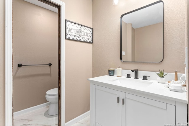 bathroom with marble look tile flooring, vanity, toilet, and baseboards