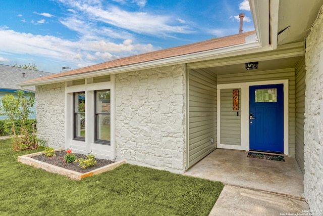 view of exterior entry featuring stone siding and a lawn