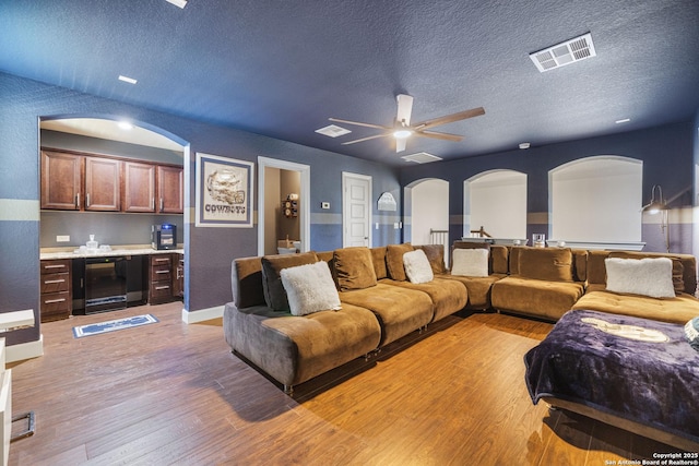 4438 Saddle Spur, San Antonio, TX 78253 - living room featuring wine cooler, a textured ceiling, light wood-style flooring, arched walkways, and bar