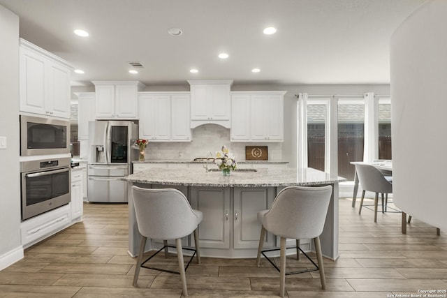 8823 Hideout, San Antonio, TX 78254 - kitchen with appliances with stainless steel finishes, white cabinetry, backsplash, light wood-style flooring, and recessed lighting
