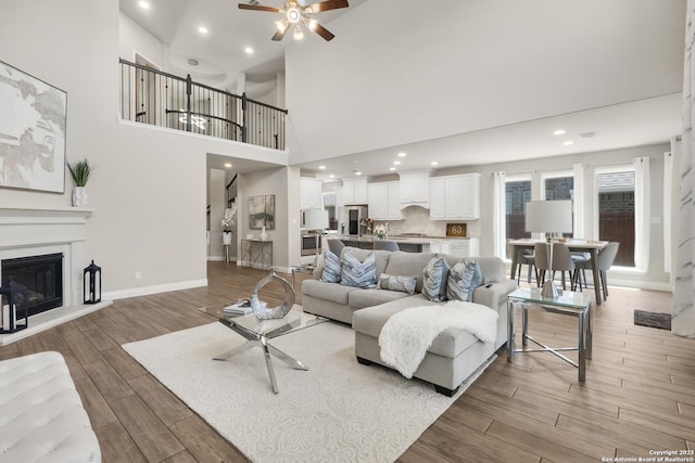 8823 Hideout, San Antonio, TX 78254 - living area featuring light wood-type flooring, a ceiling fan, a glass covered fireplace, baseboards, and recessed lighting